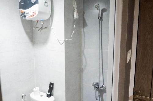 a bathroom with a shower with a toilet and a sink at Modern Spacious Studio Room Apartment at Taman Melati Surabaya By Travelio in Surabaya