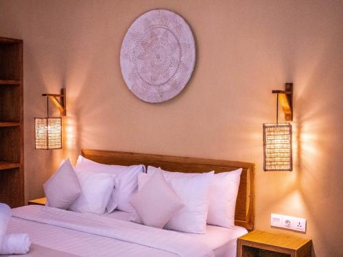 um quarto com uma cama grande e almofadas brancas em Mango Lodge em Selong Blanak