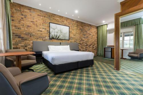 una camera d'albergo con letto e muro di mattoni di The Carrington Inn - Bungendore a Bungendore