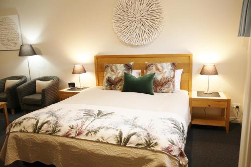 a bedroom with a bed and a chair and lamps at Motel On A'Beckett in Inverloch