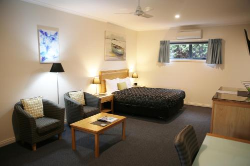 Habitación de hotel con cama y silla en Motel On A'Beckett, en Inverloch