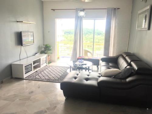 sala de estar con sofá de cuero y mesa en Amaryllis guest house PD en Port Dickson