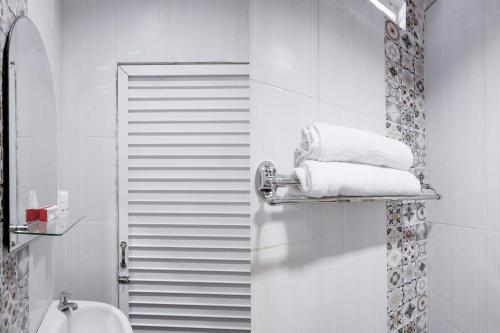 ein weißes Bad mit einem Handtuchhalter neben einem Waschbecken in der Unterkunft Super OYO 621 Vania Residence in Medan