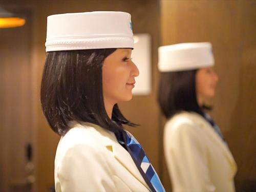 a woman in uniform in front of a mirror at Henn na Hotel Tokyo Ginza in Tokyo