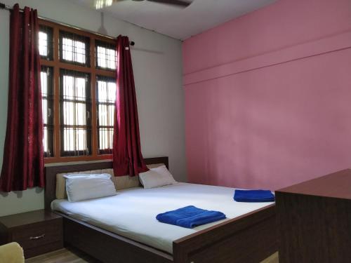 Bett in einem Zimmer mit einer rosa Wand in der Unterkunft Bagori Resort-Best Holiday Resort in Kaziranga in Sakmuthi