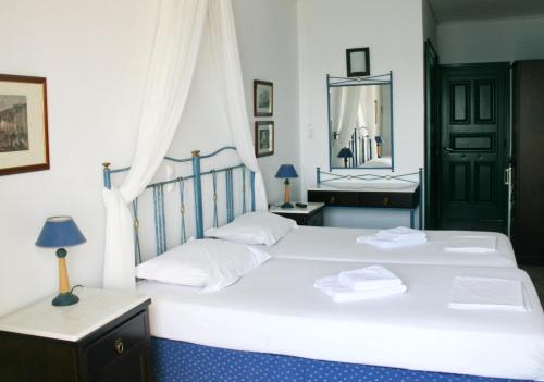 a bedroom with two white beds and a mirror at Dionysos Hotel in Skala