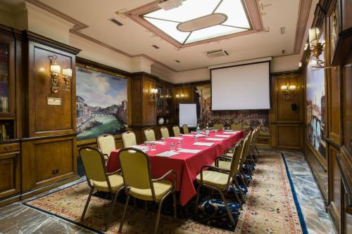 a conference room with a table and chairs and a projection screen at Adler Cavalieri Hotel-Private Spa & Gym in Florence