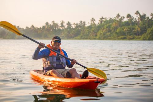 a man is in a kayak on the water at Lhasa Ayurveda and Wellness Resort - A BluSalzz Collection, Kochi, Kerala in Cochin
