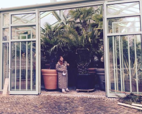 a woman standing inside of a greenhouse with plants at Wilsmann Apartmentvermietung in Hövelhof