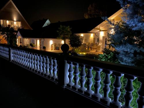 a white fence in front of a house at night at Wilsmann Apartmentvermietung in Hövelhof