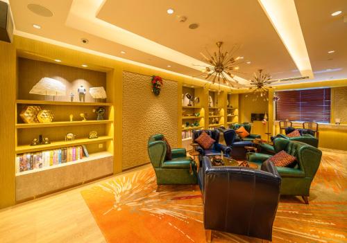 una sala de estar con sillas verdes y una biblioteca. en Grand Dragon Hotel, en Macau