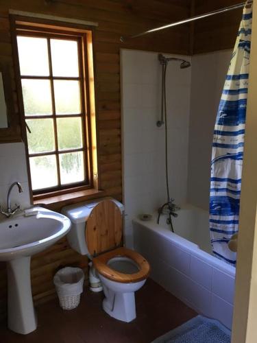 a bathroom with a wooden toilet and a sink at Riversong Farm in Stilbaai