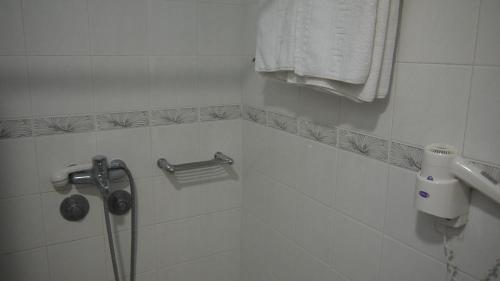 a white tiled bathroom with a shower and towel at Fani Hotel in Loutra Edipsou
