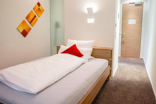a bedroom with a bed with a red pillow on it at Gasthof Krone in Bissingen