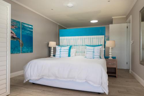a bedroom with a large white bed with blue accents at The Sugar Shack in Ballito