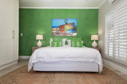a bedroom with a white bed and green walls at The Sugar Shack in Ballito