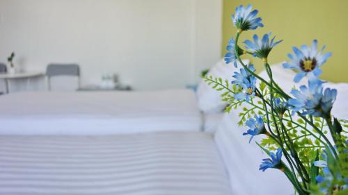 a vase filled with blue flowers next to a bed at Kata Bai D - SHA Certificate Hotel in Kata Beach