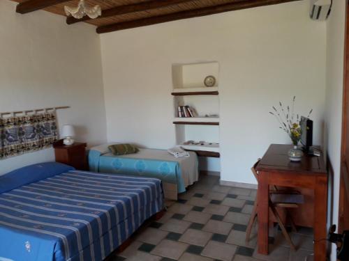 a bedroom with a bed and a table and a desk at Sa Perda Arrubia in Cardedu