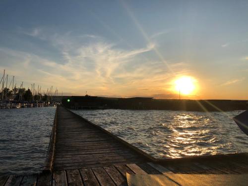 a dock with the sun setting over the water at Pension Peterhof in Mörbisch am See
