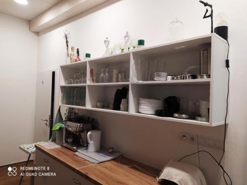 a kitchen shelf with dishes and a coffee maker at Villa Liduška s kavárnou in Bechyně
