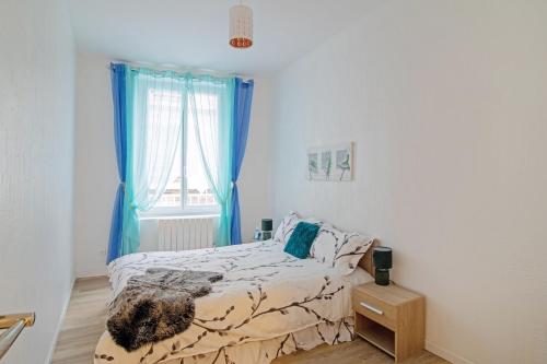 Schlafzimmer mit einem Bett und einem Fenster mit blauen Vorhängen in der Unterkunft Le cosy fertois-self checkin-centre-ville in La Ferté-sous-Jouarre
