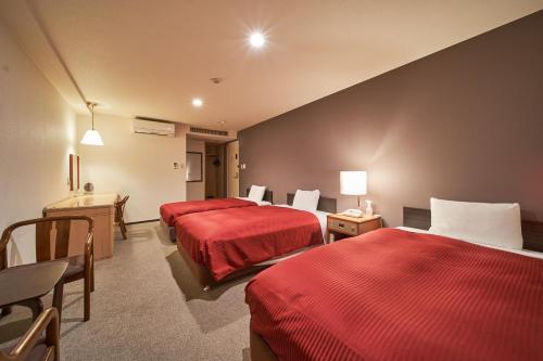 尼崎市にあるホテルファーストステイ尼崎のベッド2台とデスクが備わるホテルルームです。