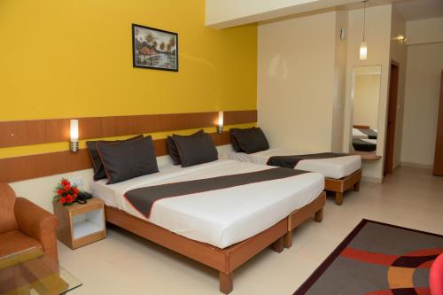 une chambre d'hôtel avec deux lits et un canapé dans l'établissement Hotel Casa Meridian, à Vānivilāsa Puram