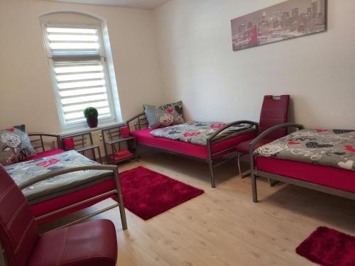 um quarto com 3 camas e uma cadeira e uma janela em Apartments Irena Burkert em Chemnitz