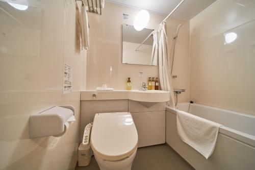 a white bathroom with a toilet and a sink at Hotel First Stay Amagasaki in Amagasaki