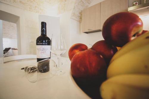 a bottle of wine and a bowl of apples and a glass at MASSERIA SCALEDDA in Manduria