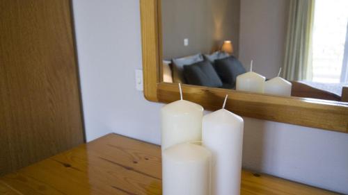 a group of white candles on a table in front of a mirror at Fani Hotel in Loutra Edipsou