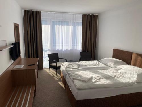 テプリツェにあるHotel Panoramaのベッド、デスク、窓が備わるホテルルームです。