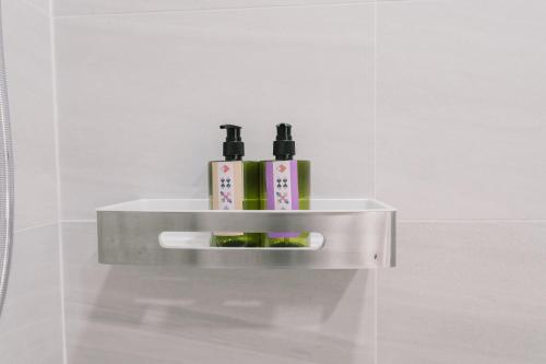 a shelf in a bathroom with three bottles on it at B Innspire Hotel in Chiang Mai