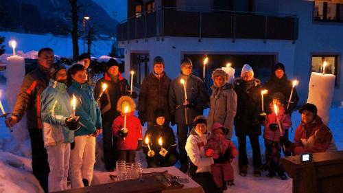 a group of people standing in the snow holding lit candles at Pension Alpina in Reith im Alpbachtal