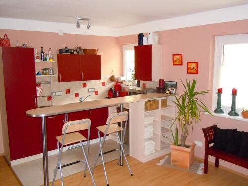 eine Küche mit roten Schränken und einer Theke mit Stühlen in der Unterkunft Seegarten Appartements in Feld am See