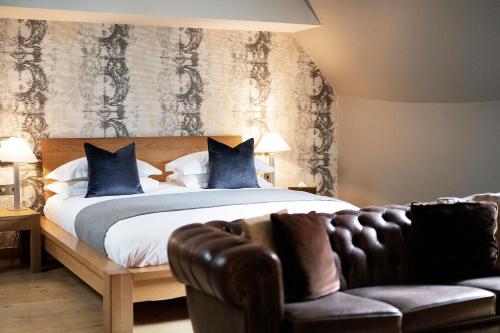 a bedroom with a bed and a leather couch at Hotel du Vin Henley in Henley on Thames