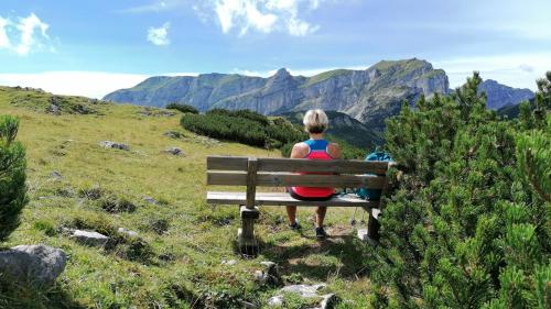 a woman sitting on a bench looking at the mountains at Pension Alpina in Reith im Alpbachtal