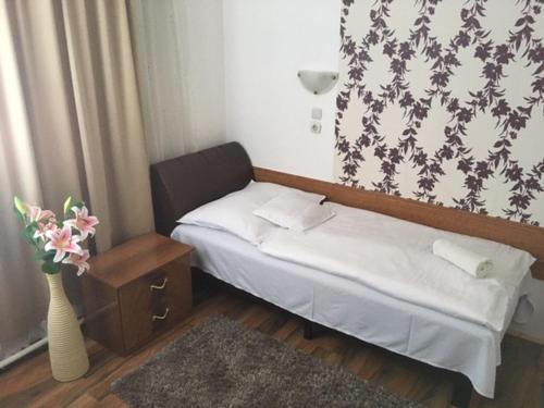a small bedroom with a bed and a vase with flowers at Európa Panzió in Mátészalka