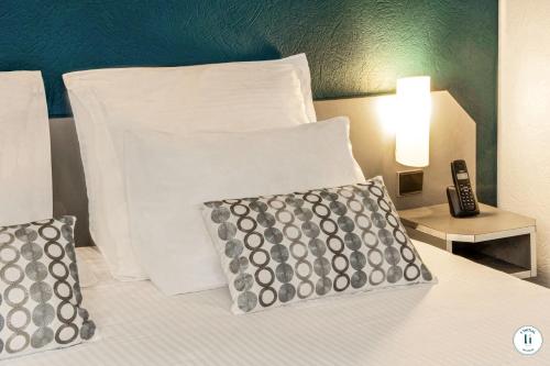 a bed with two pillows and a remote control on it at L'Initial in Toulouse