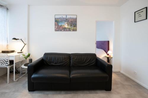 un sofá de cuero negro en una habitación con cama en Le Nazareth -Charmant appartement Lyon Part-Dieu balcon garage, en Lyon