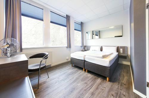 a hotel room with a bed and a desk and window at Road House Hotel in Paderborn