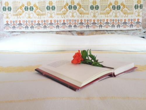 an open book with a flower on a bed at Sa Perda Arrubia in Cardedu
