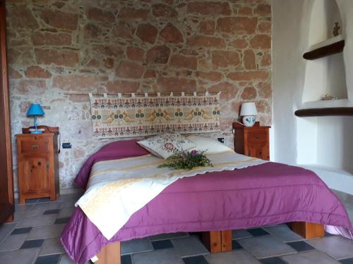 a bedroom with a bed in a stone wall at Sa Perda Arrubia in Cardedu