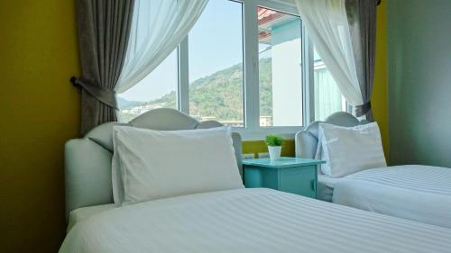 a bedroom with two beds and a window at Kata Bai D - SHA Certificate Hotel in Kata Beach