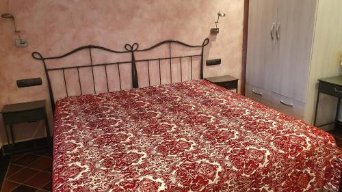 a bed with a red and white bedspread on it at Hotel Restaurant El Bosc in Banyeres del Penedes