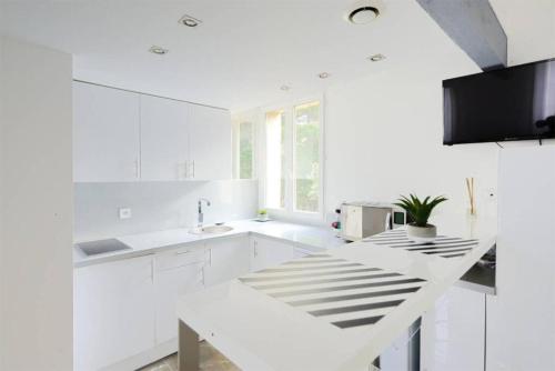 une cuisine blanche avec des armoires blanches et un évier dans l'établissement La suite de Mont-Vert (Jacuzzi privatif), à Saint-Zacharie