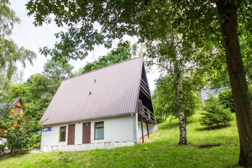 a white barn with a metal roof in a field at Ośrodek Wypoczynkowy AKWA Marina in Nysa