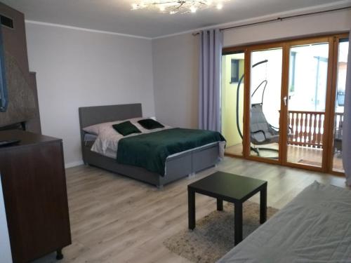 a bedroom with a bed and a table and a balcony at Domek pod świerkami in Kudowa-Zdrój