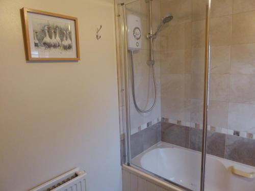 La salle de bains est pourvue d'une douche et d'une baignoire. dans l'établissement Herriot's Nook, à Thirsk