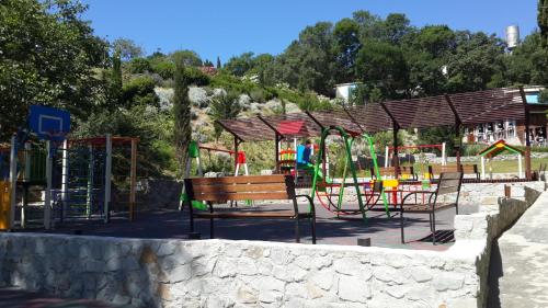 a park with a playground with a bench and swings at Zeleny Mis in Alupka